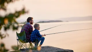 Father and son fishing by a lake at sunset