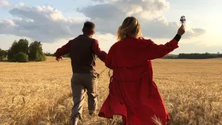 Couple running through a wheat field.