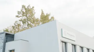 White building exterior with logo and trees.