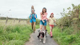 Young family walking a dog down a path