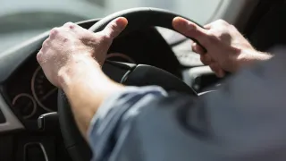 Close-up of hands holding a steering wheel.