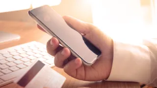 Hand holding a phone and a credit card.