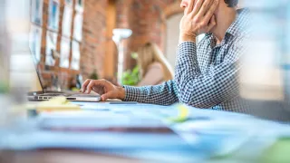 Man working on computer, hand on face