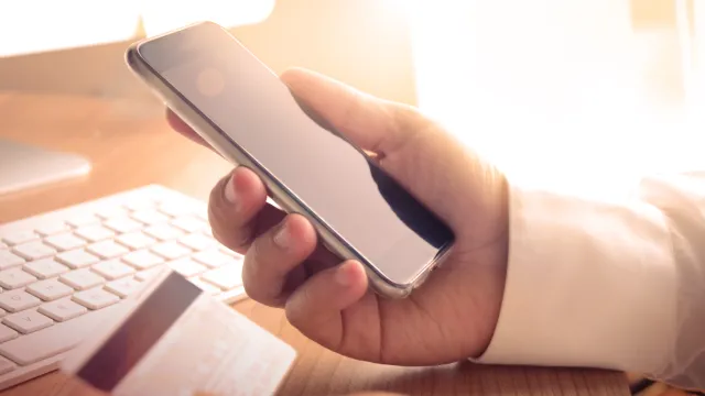 Hand holding a phone and a credit card.