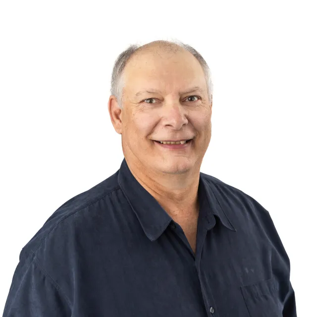 Smiling man wearing a dark blue shirt.