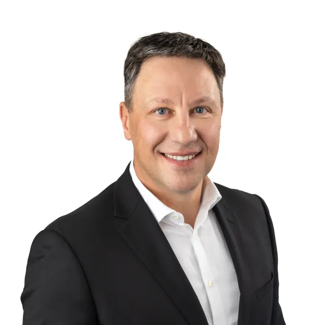 Headshot of a smiling man wearing a suit jacket and white shirt.